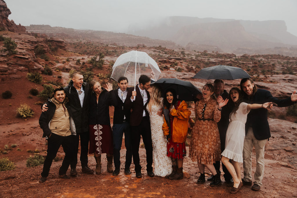 Bride and groom kissing with their family at their elopement in Moab Utah desert