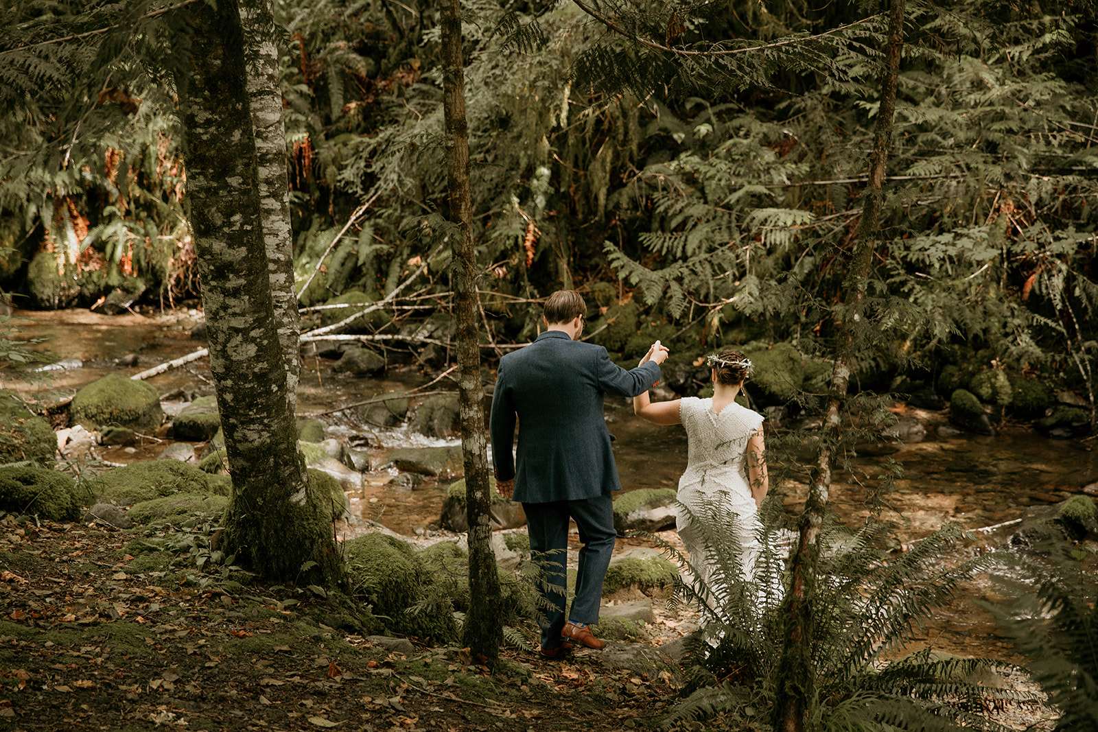 bride and groom crossing a creek at the mt. rainier elopement