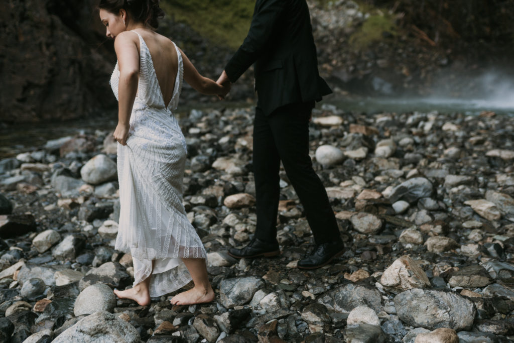 bride and groom hiking at a waterfall in olympic national park