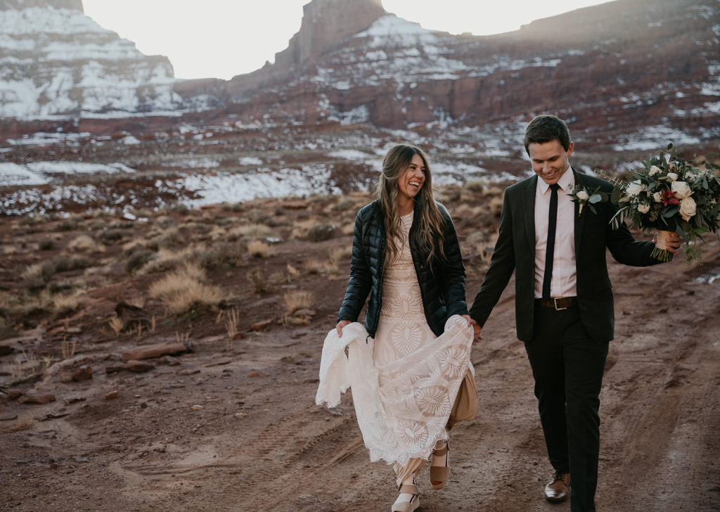bride and groom hiking in wedding clothes at their elopement in Moab Utah 