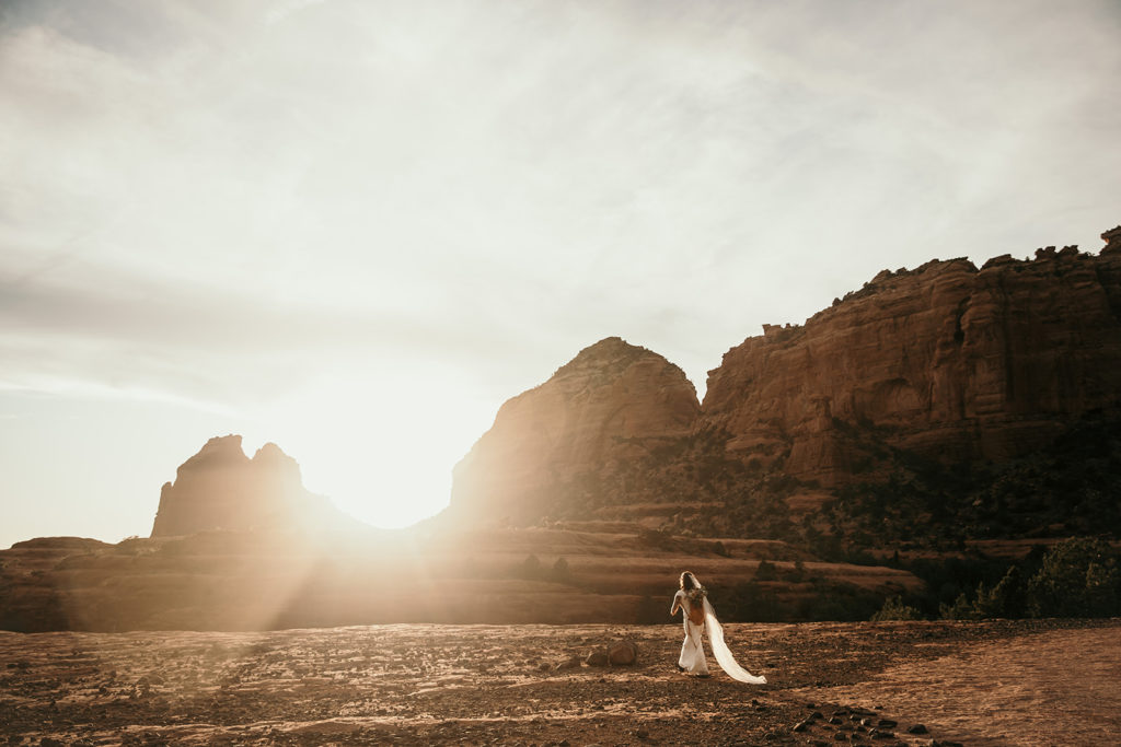 bride hiking into the sunset at her elopement in sedona, arizona