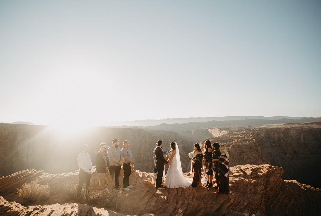 bride and groom standing with their families during their wedding ceremony at horseshoe bend, arizona