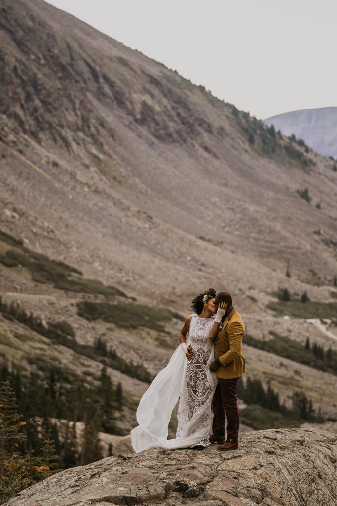 Bride and groom kissing on the cliff of a mountain at their elopement in Breckenridge Colorado
