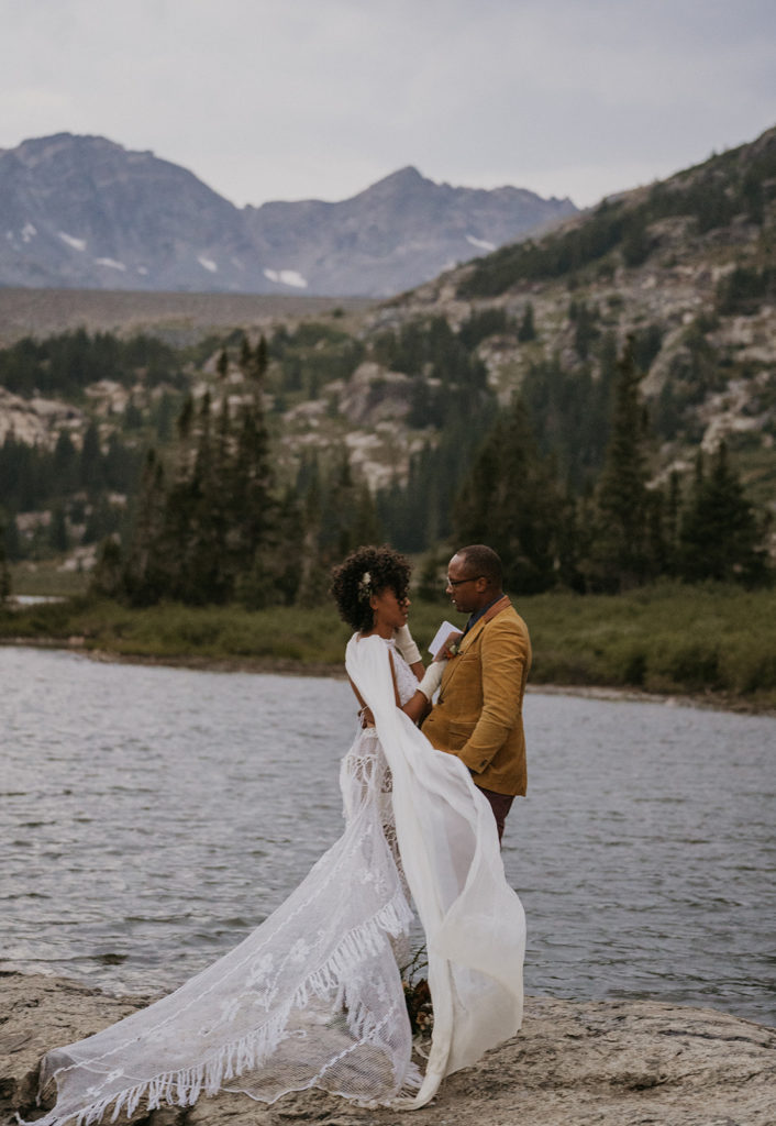 Bride and groom exchanging their wedding vows on the edge of a lake with mountains in the background in Breckenridge Colorado