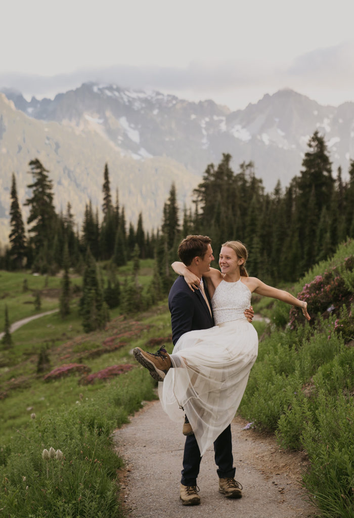 groom is picking up bride with big smiles on a trail at mount rainier national park