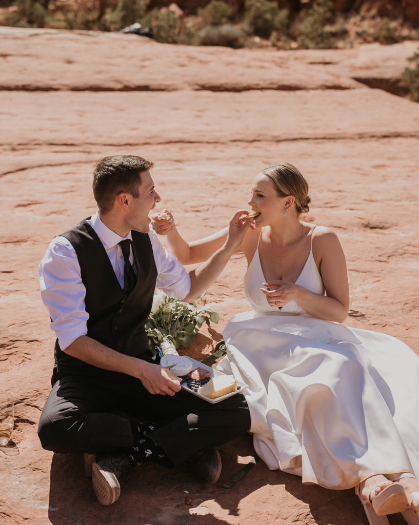 bride and groom eating a charcuterie board at their elopement in sedona arizona
