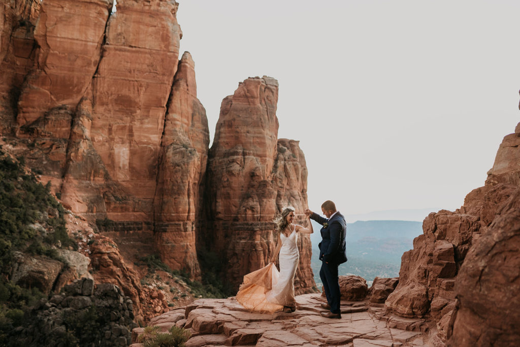 bride and groom dancing on red rock cliff edge at their sedona arizona elopement