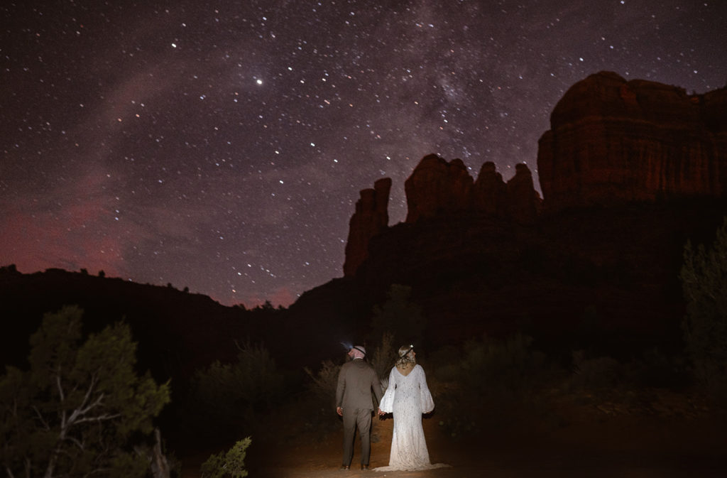 bride and groom standing in the dark with headlamps on with the Milky Way stars in the background on their sedona arizona elopement day