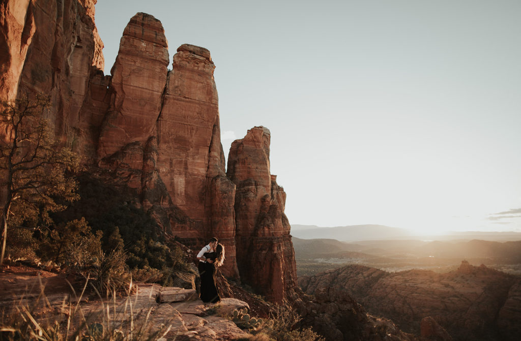 couple kissing with the sun set in the background at the cathedral rock engagement session
