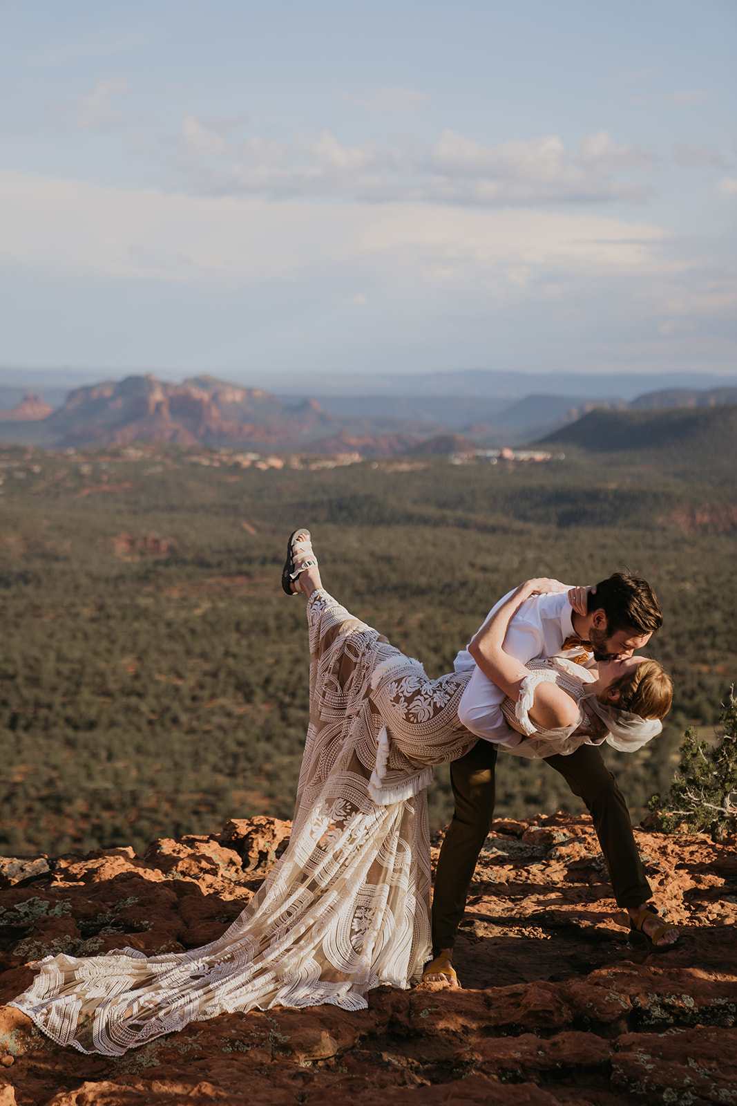 bride and groom kissing in a dip on the top of a mountain overlooking sedona arizona